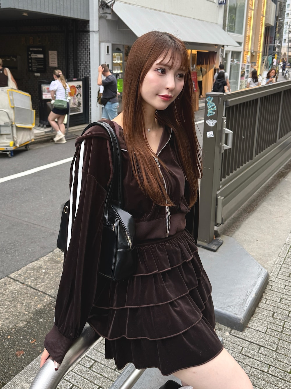 ブラウン系のスカート、ブラウン系のパーカー、ブラック系のハンドバッグを着用したレディースの秋コーディネートの2枚目の写真