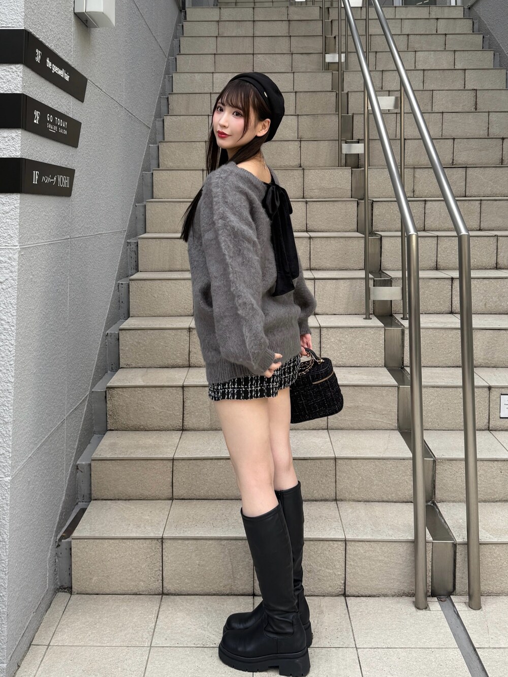 グレー系のニット/セーター、ブラック系のショルダーバッグ、ブラック系のブーツを着用したレディースの秋コーディネートの4枚目の写真