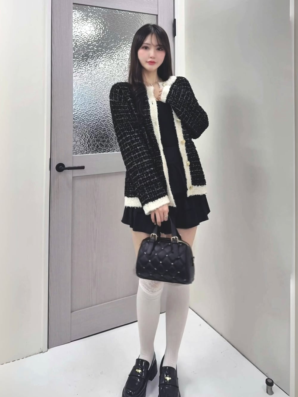 ブラック系のカーディガン/ボレロ、ブラック系のスカート、ブラック系のボストンバッグを着用したレディースの冬コーディネートの2枚目の写真