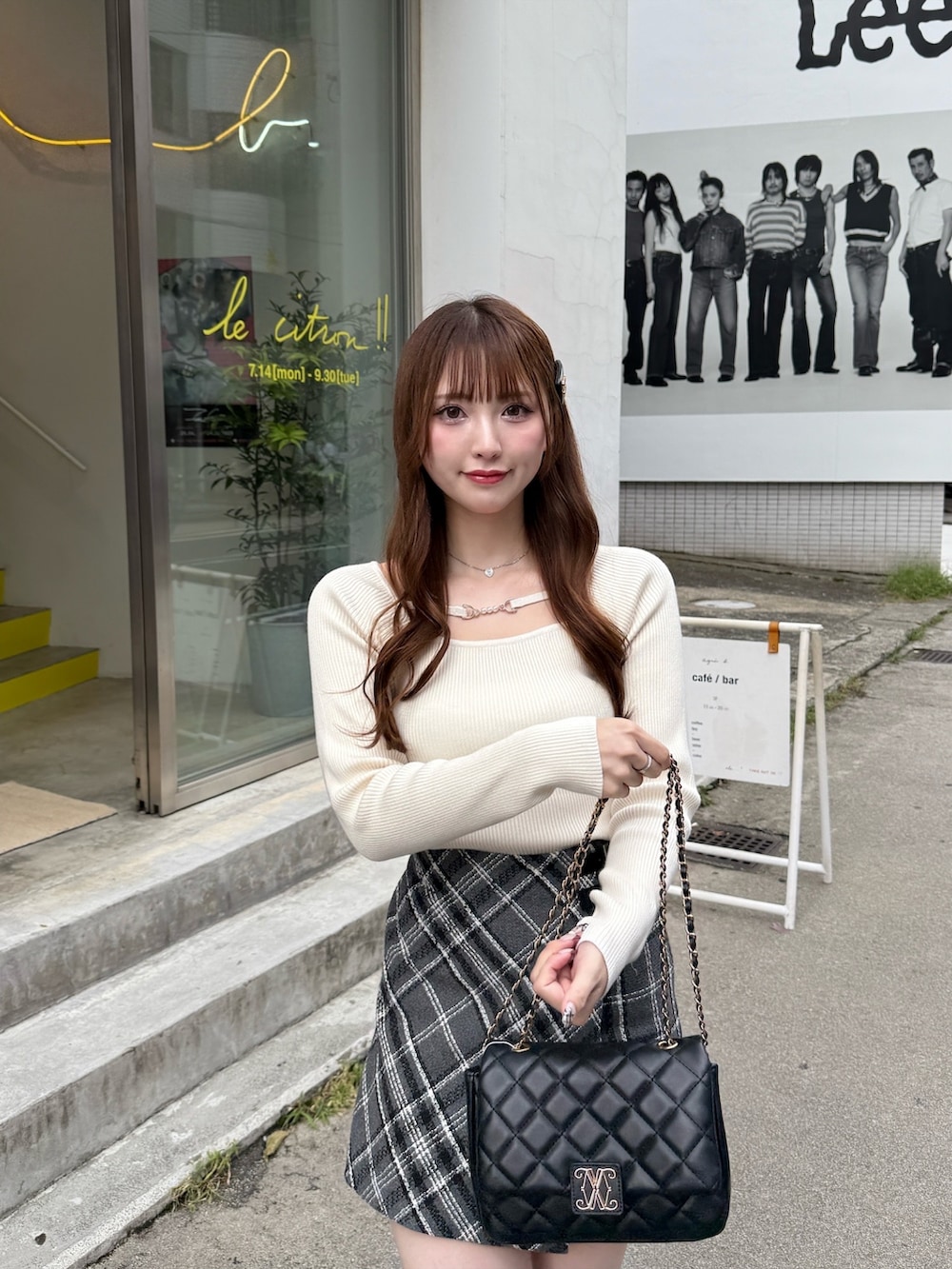 グレー系のスカート、ホワイト系のニット/セーター、ブラック系のブーツを着用したレディースの秋コーディネートの3枚目の写真