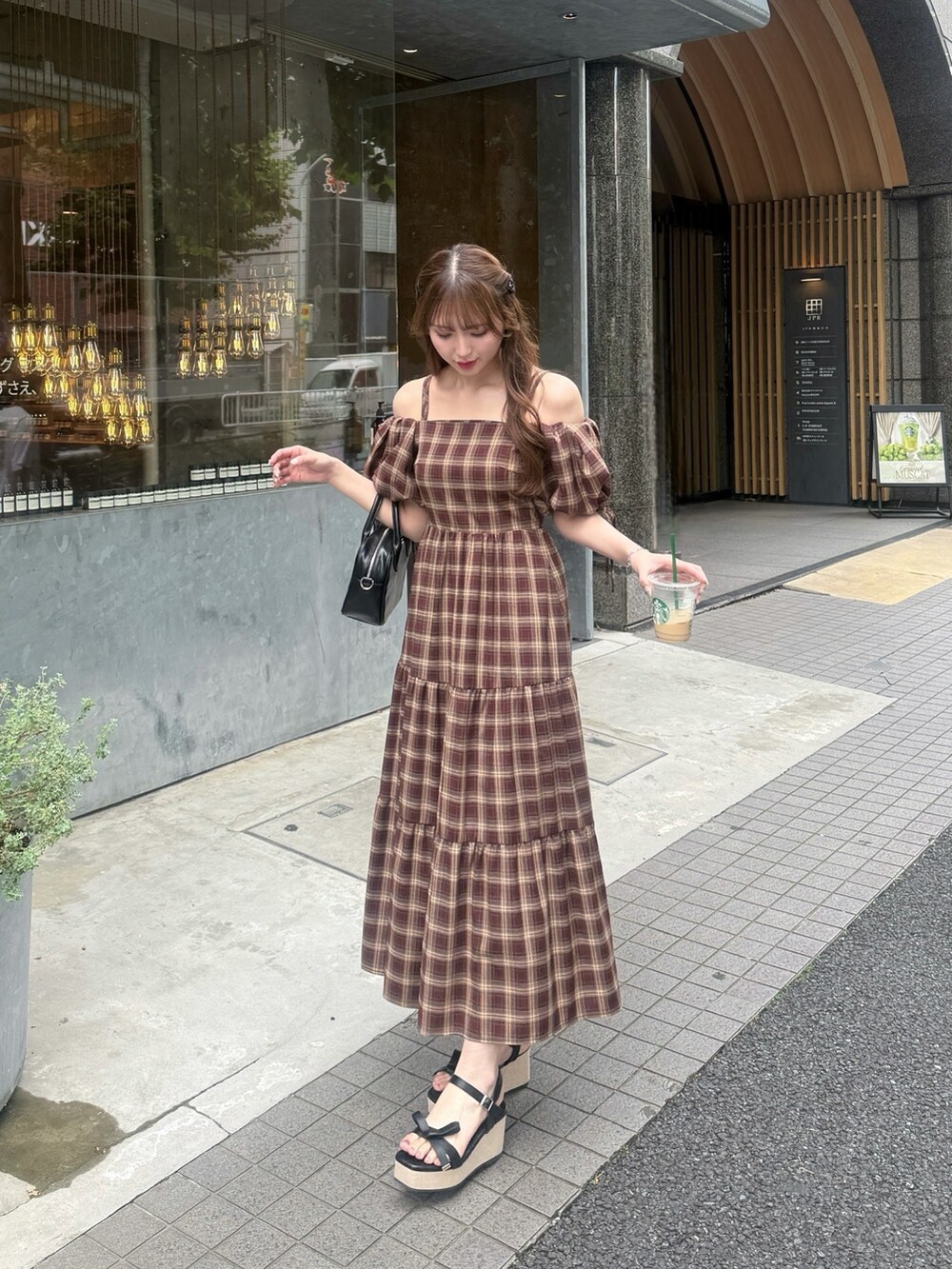 レッド系のワンピース、ブラック系のハンドバッグ、ブラック系のサンダルを着用したレディースの夏コーディネートの2枚目の写真