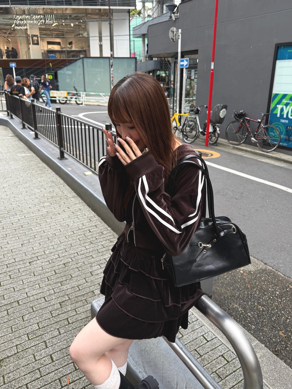 ブラウン系のスカート、ブラウン系のパーカー、ブラック系のハンドバッグを着用したレディースの秋コーディネートの4枚目の写真