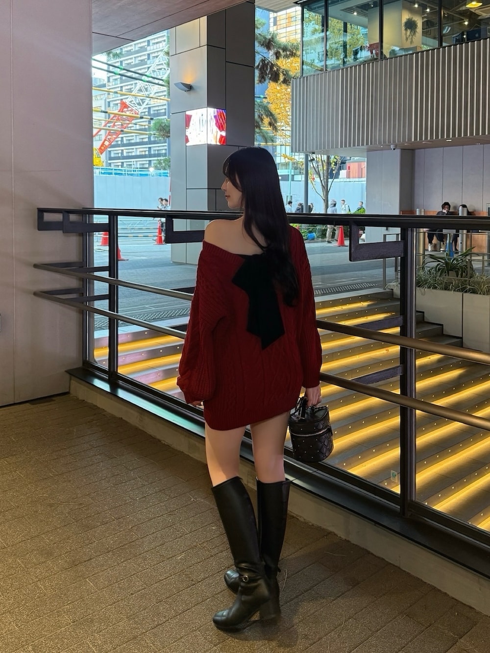 レッド系のニット/セーター、ブラック系のその他パンツ、ブラック系のブーツを着用したレディースの秋コーディネートの2枚目の写真