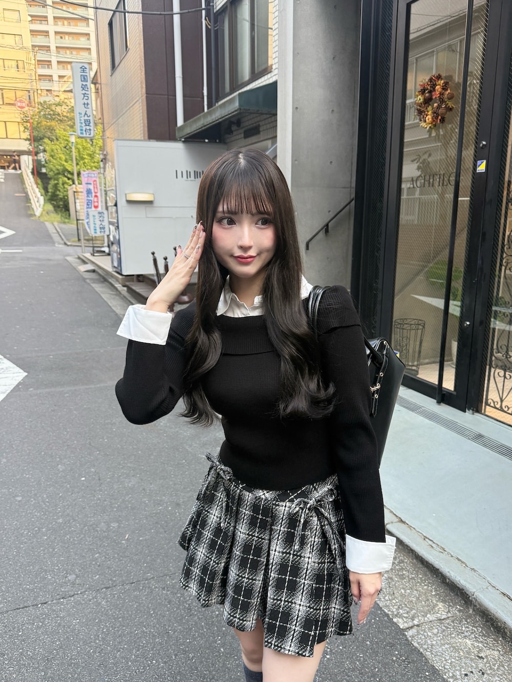 ブラック系のスカート、ブラック系のニット/セーター、ブラック系のハンドバッグを着用したレディースの秋コーディネートの2枚目の写真