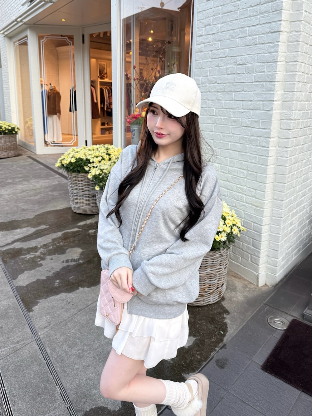 グレー系のパーカー、ホワイト系のスカート、ピンク系のショルダーバッグを着用したレディースの冬コーディネートの2枚目の写真