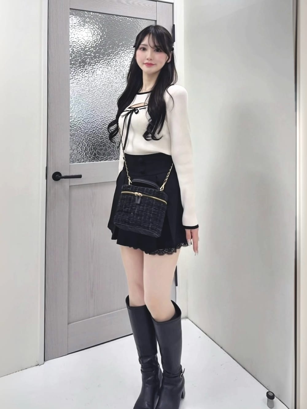 ホワイト系のニット/セーター、ブラック系のスカート、ブラック系のショルダーバッグを着用したレディースの冬コーディネートの2枚目の写真