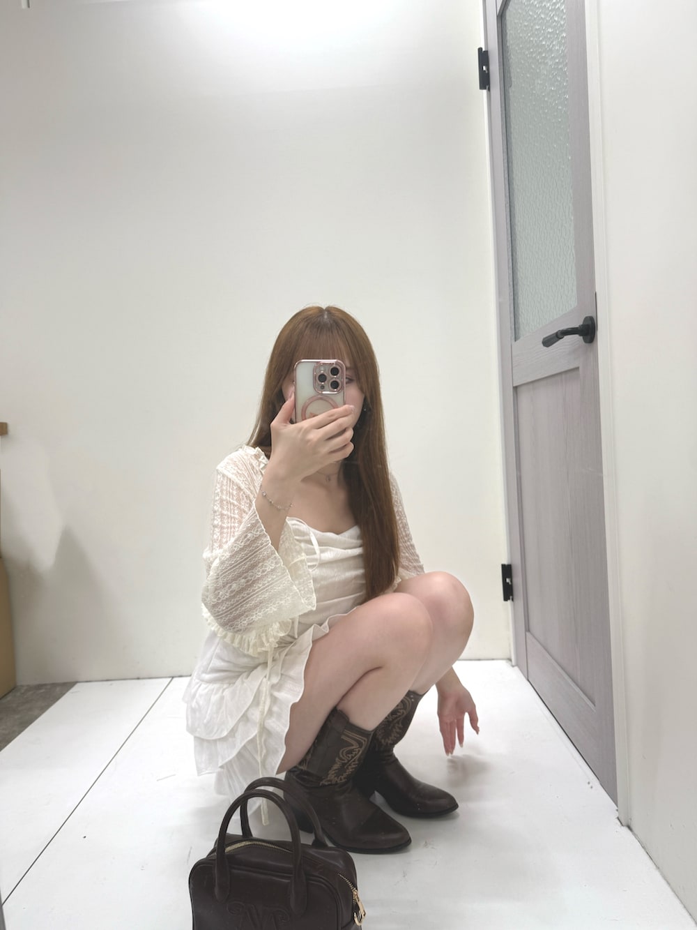 ホワイト系のワンピース、ホワイト系のカーディガン/ボレロ、ブラウン系のハンドバッグを着用したレディースの夏コーディネートの2枚目の写真