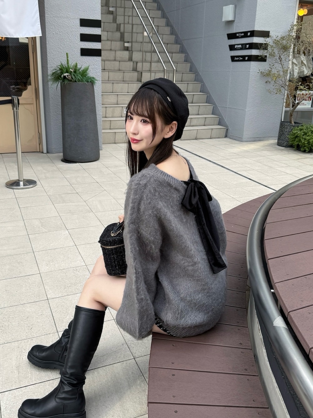 グレー系のニット/セーター、ブラック系のショルダーバッグ、ブラック系のブーツを着用したレディースの秋コーディネートの2枚目の写真