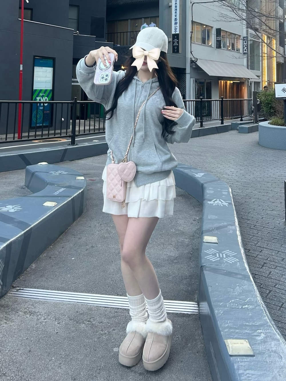 グレー系のパーカー、ホワイト系のスカート、ピンク系のショルダーバッグを着用したレディースの冬コーディネートの3枚目の写真