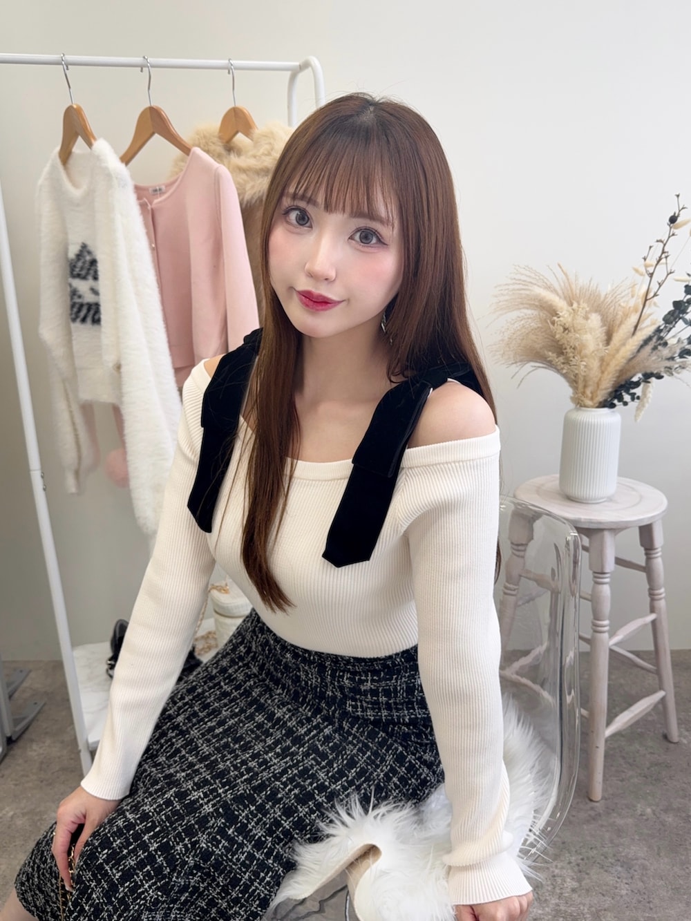 ブラック系のショルダーバッグ、ホワイト系のニット/セーター、ブラック系のスカートを着用したレディースの秋コーディネートの4枚目の写真