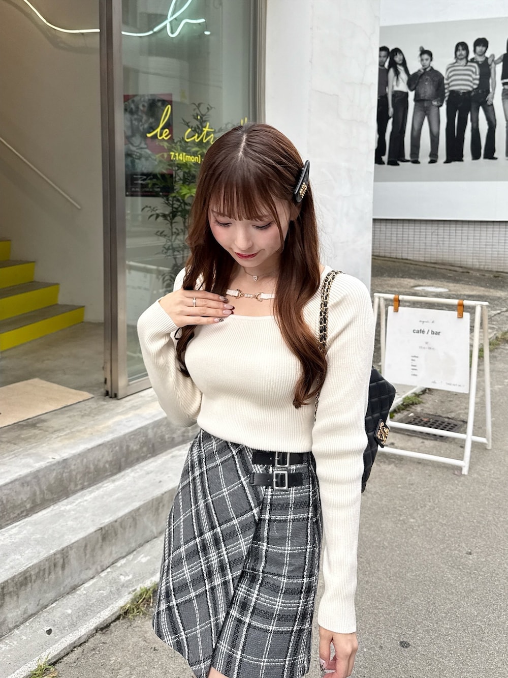 グレー系のスカート、ホワイト系のニット/セーター、ブラック系のブーツを着用したレディースの秋コーディネートの2枚目の写真