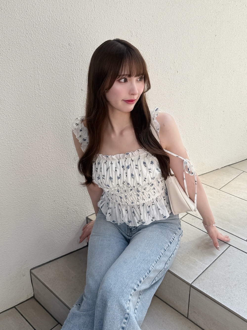 ブルー系のデニムパンツ、ホワイト系のシャツ/ブラウス、ホワイト系のサンダルを着用したレディースの夏コーディネートの3枚目の写真