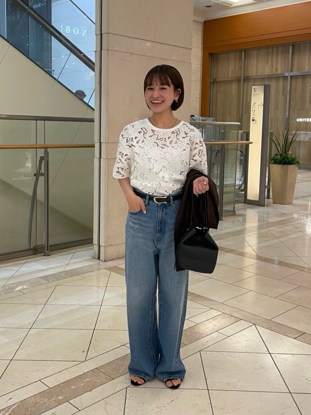 ホワイト系のシャツ/ブラウス、ブラウン系のテーラードジャケット、ブルー系のデニムパンツを着用したレディースの秋コーディネートの3枚目の写真