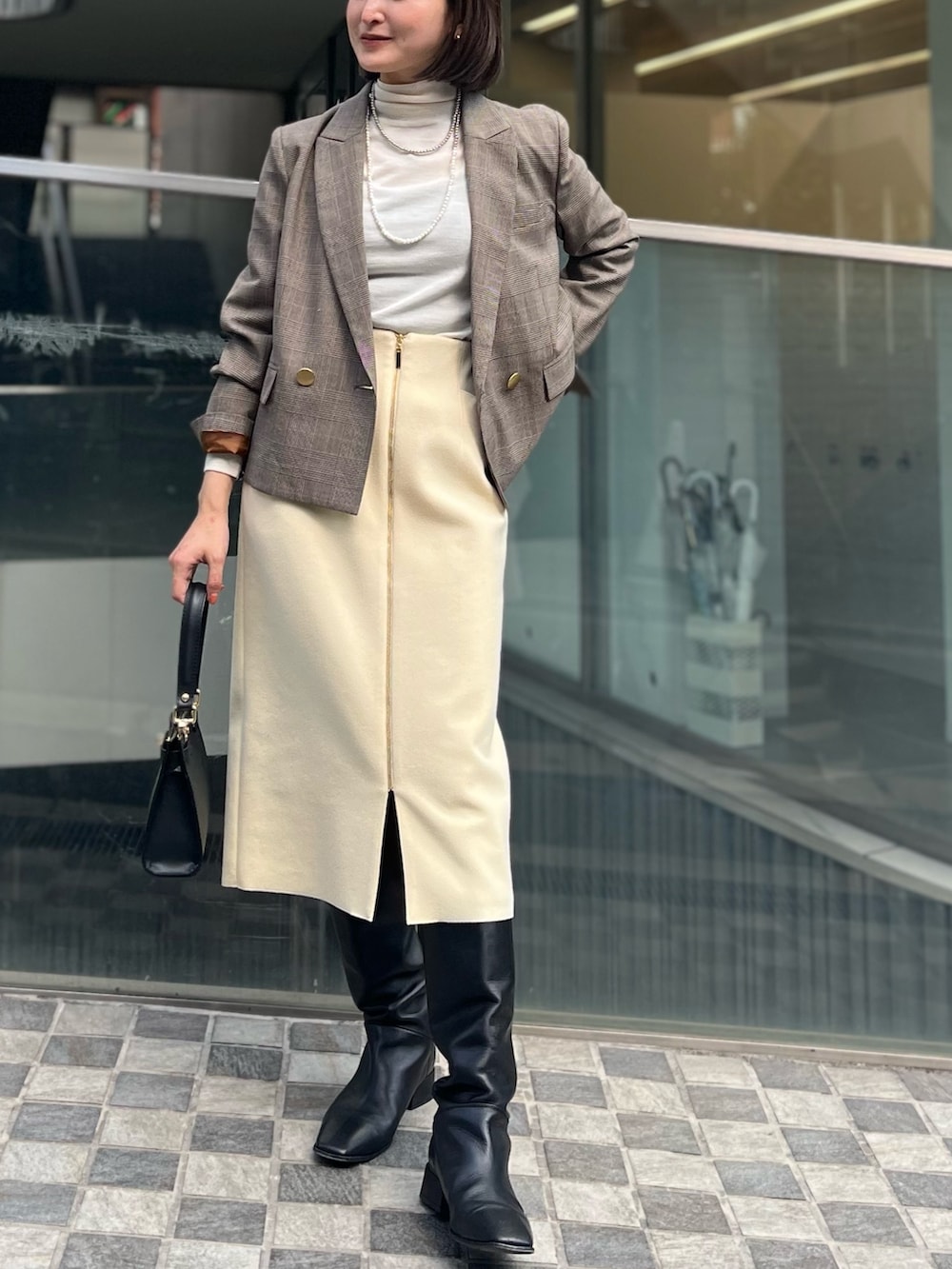 ベージュ系のテーラードジャケット、ホワイト系のニット/セーター、イエロー系のスカートを着用したレディースの冬コーディネートの2枚目の写真