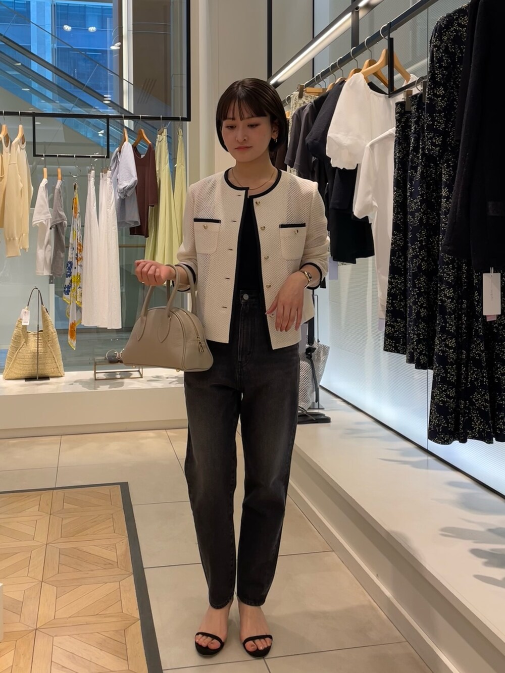 ホワイト系のノーカラージャケット、ブラック系のデニムパンツ、ベージュ系のボストンバッグを着用したレディースの春コーディネートの2枚目の写真