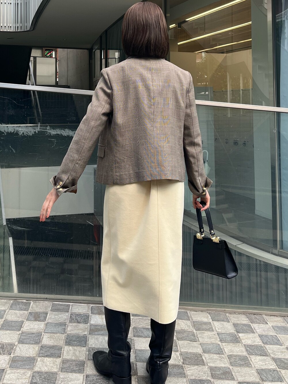 ベージュ系のテーラードジャケット、ホワイト系のニット/セーター、イエロー系のスカートを着用したレディースの冬コーディネートの6枚目の写真