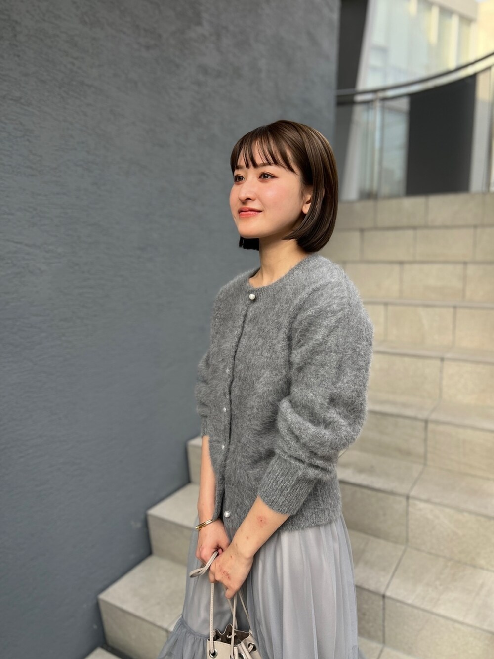 グレー系のカーディガン/ボレロ、グレー系のスカートを着用したレディースの冬コーディネートの6枚目の写真