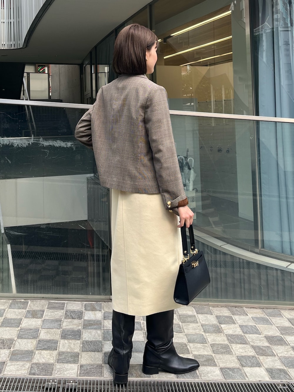 ベージュ系のテーラードジャケット、ホワイト系のニット/セーター、イエロー系のスカートを着用したレディースの冬コーディネートの5枚目の写真