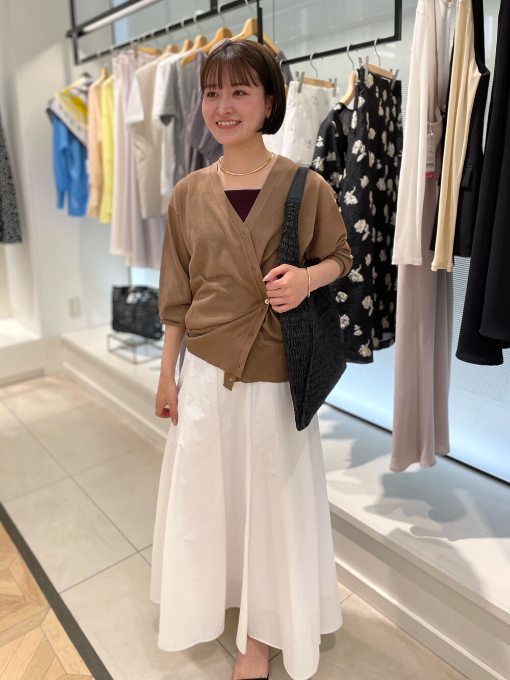 ブラウン系のカーディガン/ボレロ、ホワイト系のスカートを着用したレディースの春コーディネートの3枚目の写真