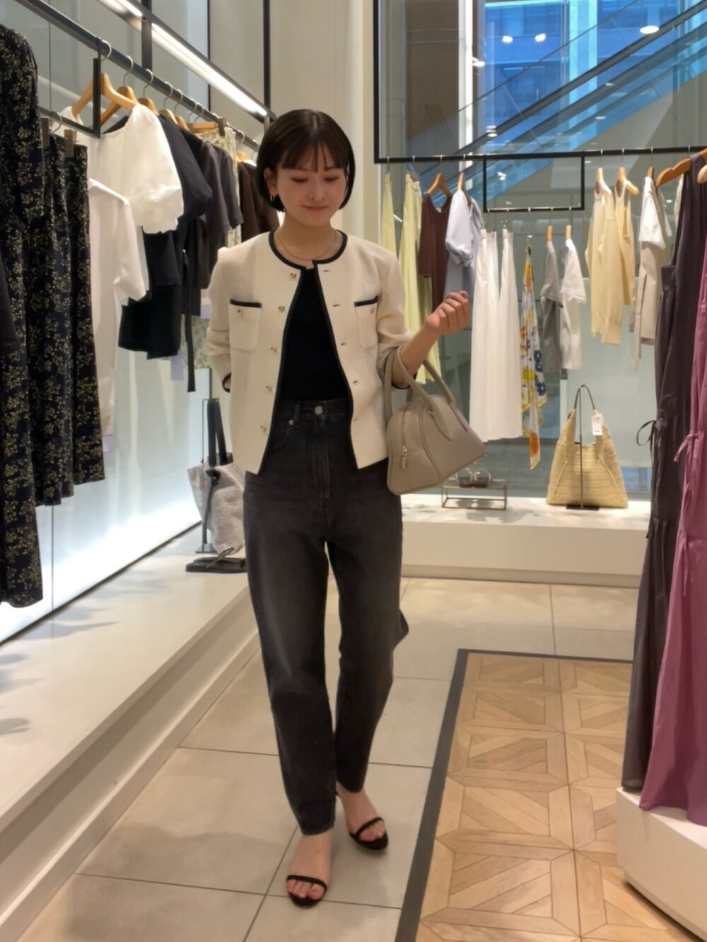 ホワイト系のノーカラージャケット、ブラック系のデニムパンツ、ベージュ系のボストンバッグを着用したレディースの春コーディネートの3枚目の写真