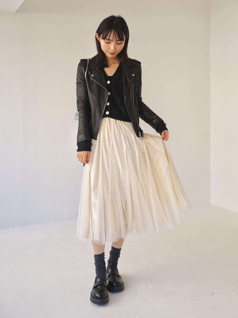 ブラック系のカーディガン/ボレロ、ベージュ系のスカートを着用したレディースの冬コーディネートの2枚目の写真