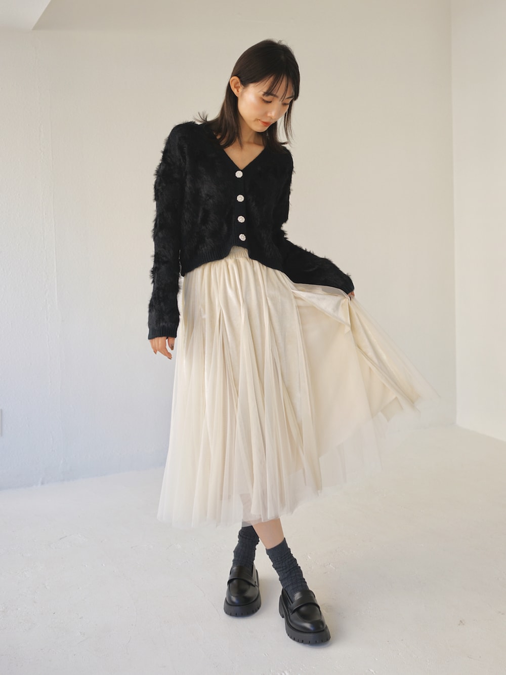 ブラック系のカーディガン/ボレロ、ベージュ系のスカートを着用したレディースの冬コーディネートの3枚目の写真