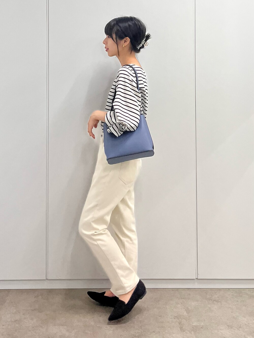 ブラック系のシャツ/ブラウス、ブルー系のショルダーバッグ、ホワイト系のデニムパンツを着用したレディースの秋コーディネートの3枚目の写真