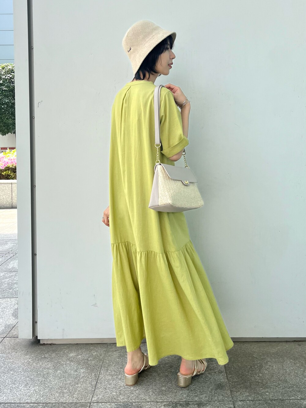 グレー系のショルダーバッグ、ゴールド系のサンダル、イエロー系のワンピースを着用したレディースの春コーディネートの3枚目の写真