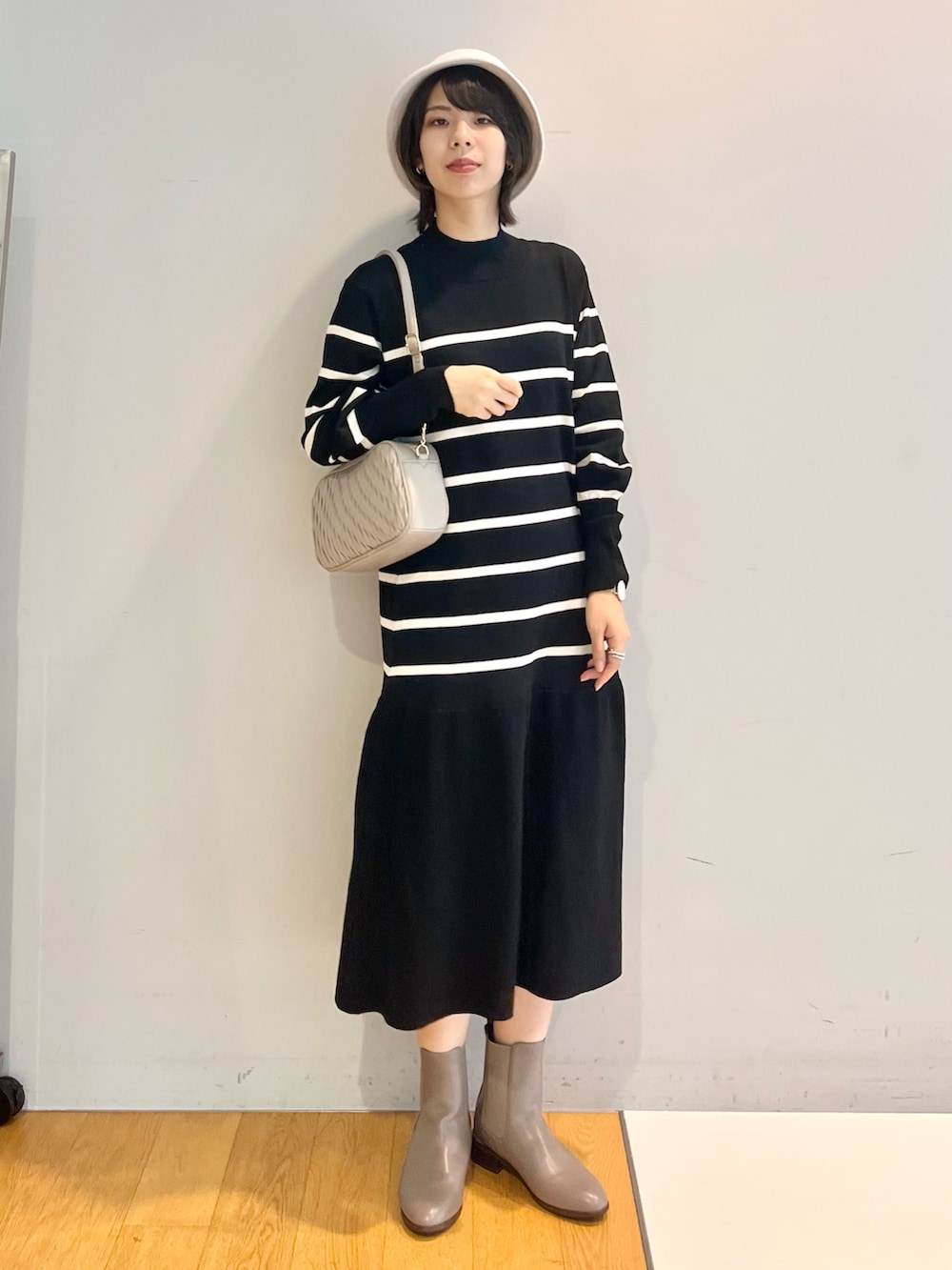 グレー系のブーツ、ホワイト系のワンピース、グレー系のショルダーバッグを着用したレディースの秋コーディネートの4枚目の写真