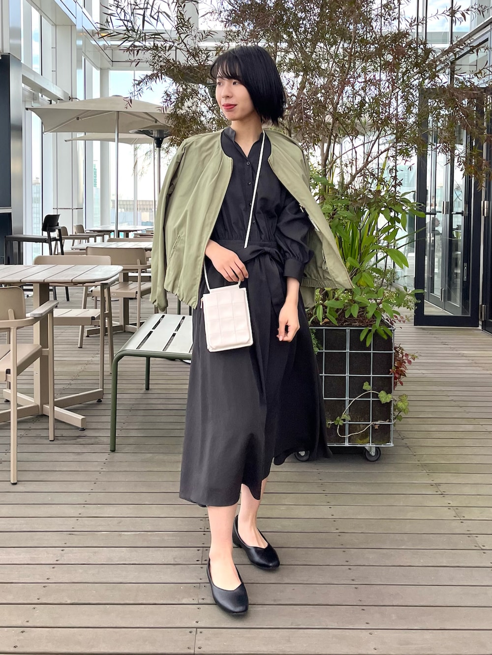 ブラック系のパンプス、ブラウン系のワンピース、グリーン系のノーカラージャケットを着用したレディースの夏コーディネートの2枚目の写真