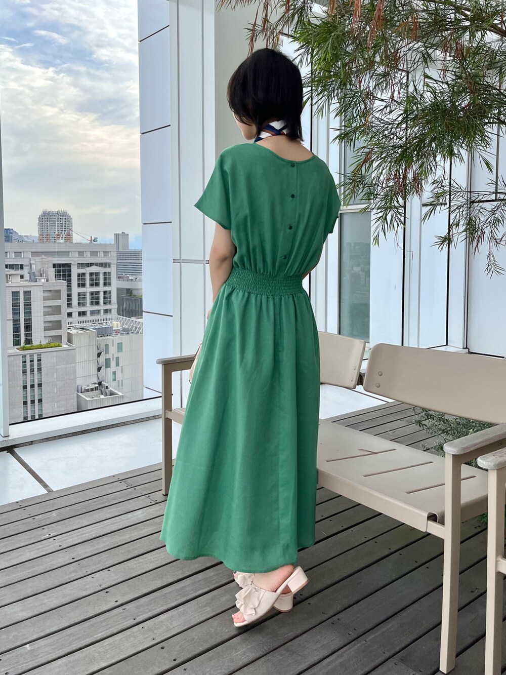 ブラック系のショルダーバッグ、ホワイト系のサンダル、グリーン系のワンピースを着用したレディースの夏コーディネートの3枚目の写真