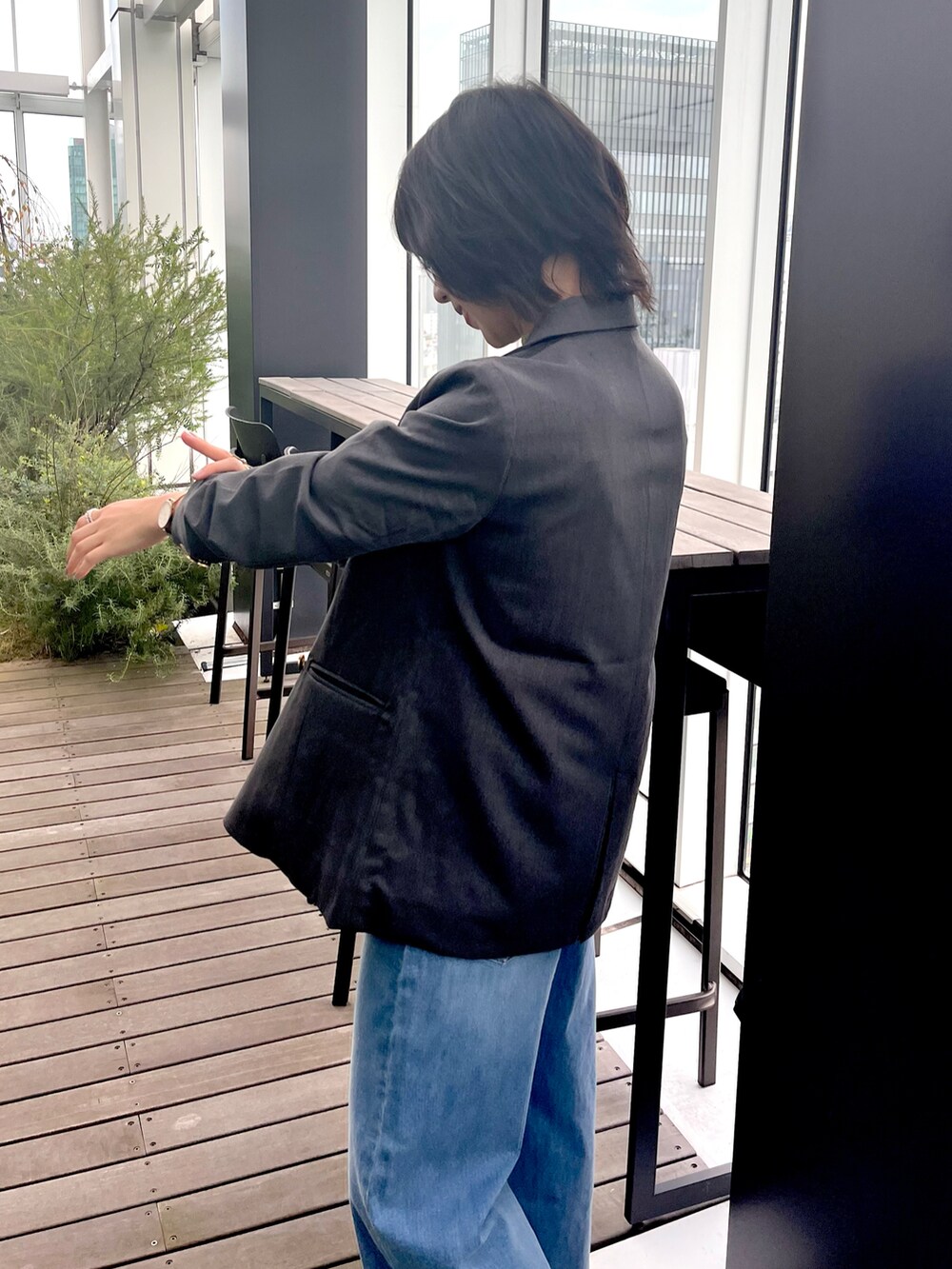 グレー系のテーラードジャケット、グリーン系のニット/セーター、ブルー系のデニムパンツを着用したレディースの秋コーディネートの4枚目の写真