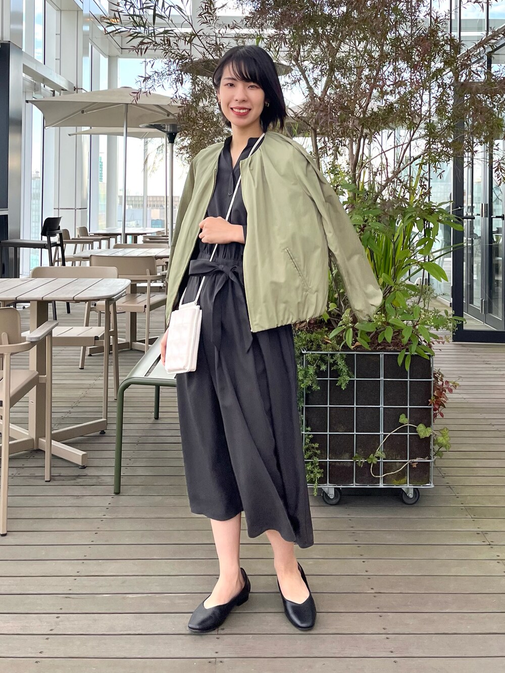 ブラック系のパンプス、ブラウン系のワンピース、グリーン系のノーカラージャケットを着用したレディースの夏コーディネートの5枚目の写真