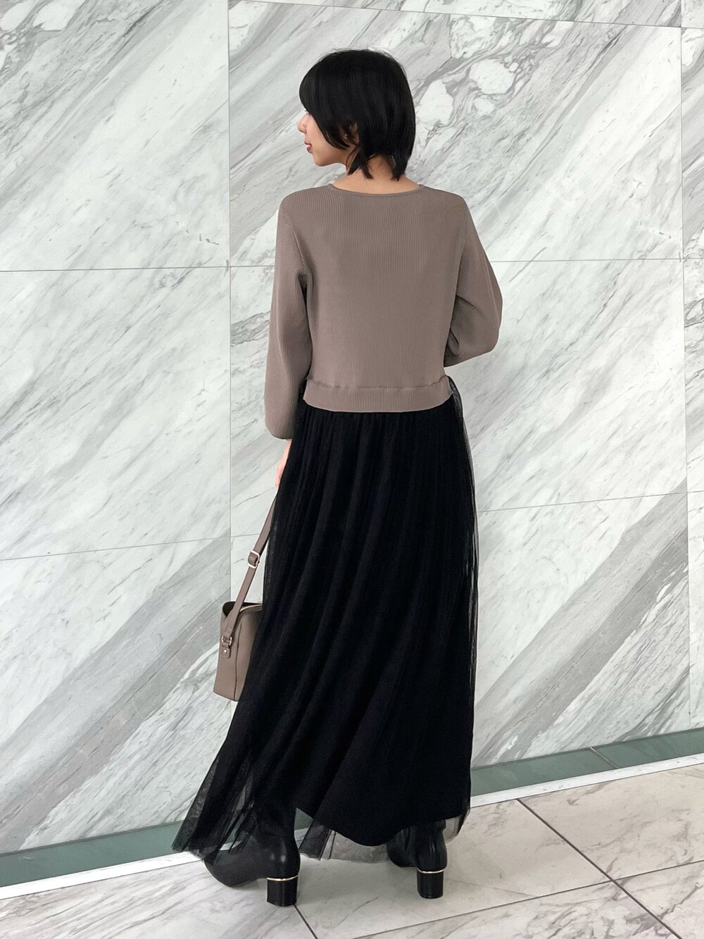 グレー系のショルダーバッグ、ブラック系のブーツ、ブラウン系のワンピースを着用したレディースの秋コーディネートの3枚目の写真