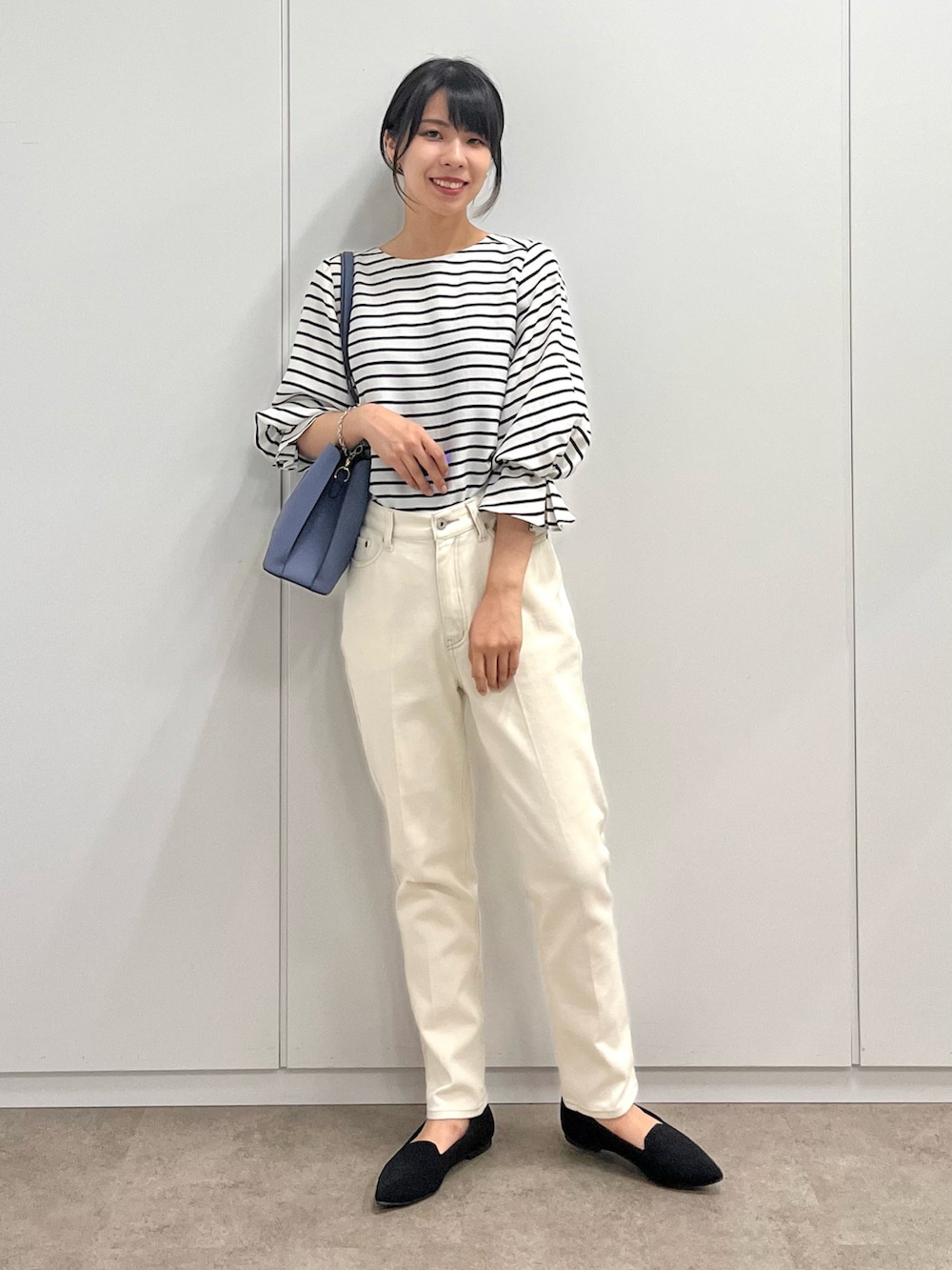 ブラック系のシャツ/ブラウス、ブルー系のショルダーバッグ、ホワイト系のデニムパンツを着用したレディースの秋コーディネートの2枚目の写真