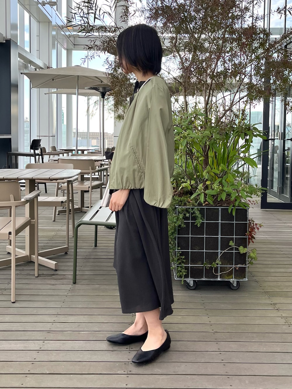 ブラック系のパンプス、ブラウン系のワンピース、グリーン系のノーカラージャケットを着用したレディースの夏コーディネートの3枚目の写真