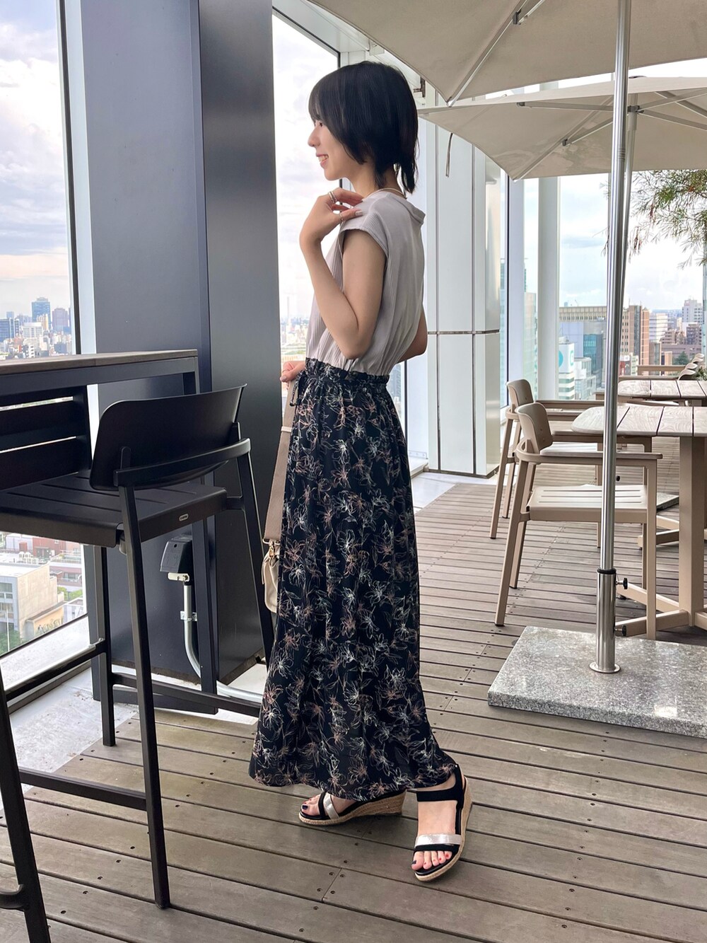 ブラック系のサンダル、ブラック系のワンピース、ホワイト系のショルダーバッグを着用したレディースの夏コーディネートの3枚目の写真