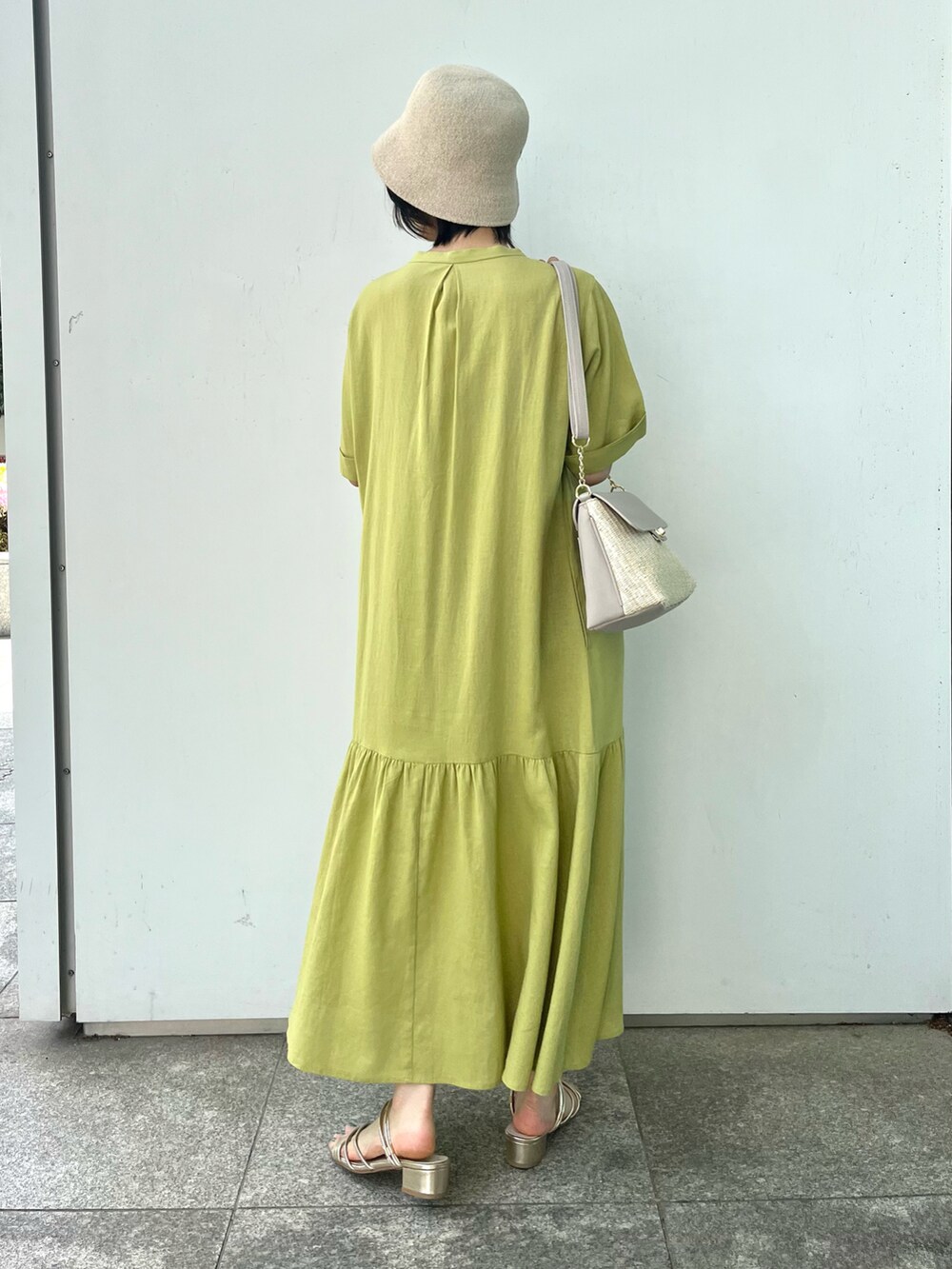 グレー系のショルダーバッグ、ゴールド系のサンダル、イエロー系のワンピースを着用したレディースの春コーディネートの4枚目の写真