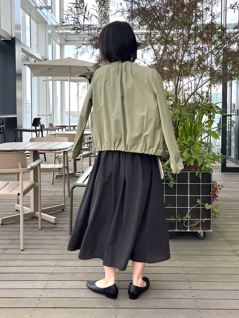 ブラック系のパンプス、ブラウン系のワンピース、グリーン系のノーカラージャケットを着用したレディースの夏コーディネートの4枚目の写真