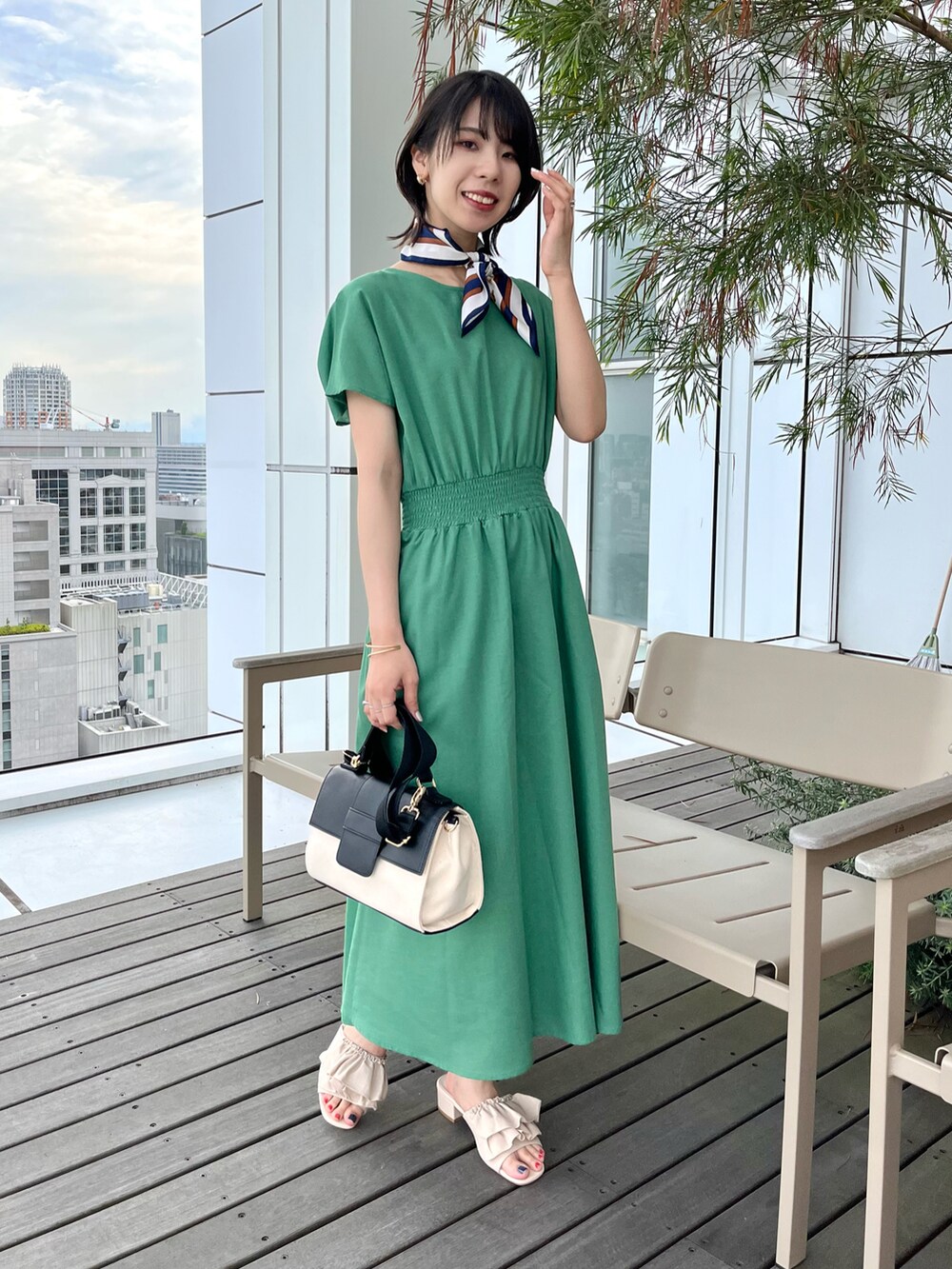 ブラック系のショルダーバッグ、ホワイト系のサンダル、グリーン系のワンピースを着用したレディースの夏コーディネートの2枚目の写真