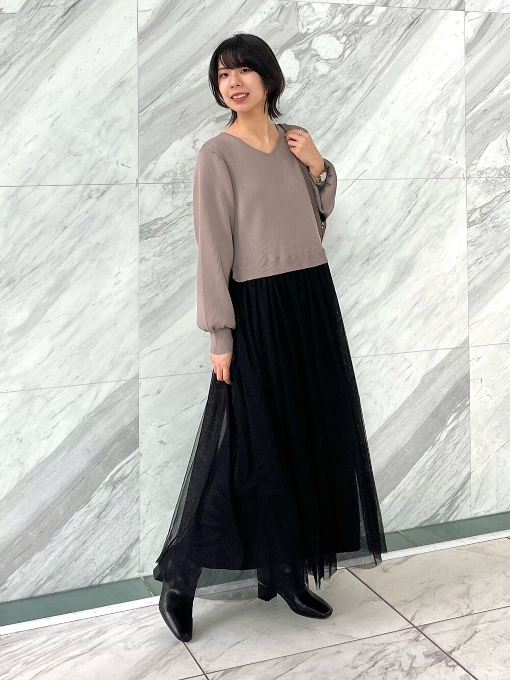 グレー系のショルダーバッグ、ブラック系のブーツ、ブラウン系のワンピースを着用したレディースの秋コーディネートの2枚目の写真