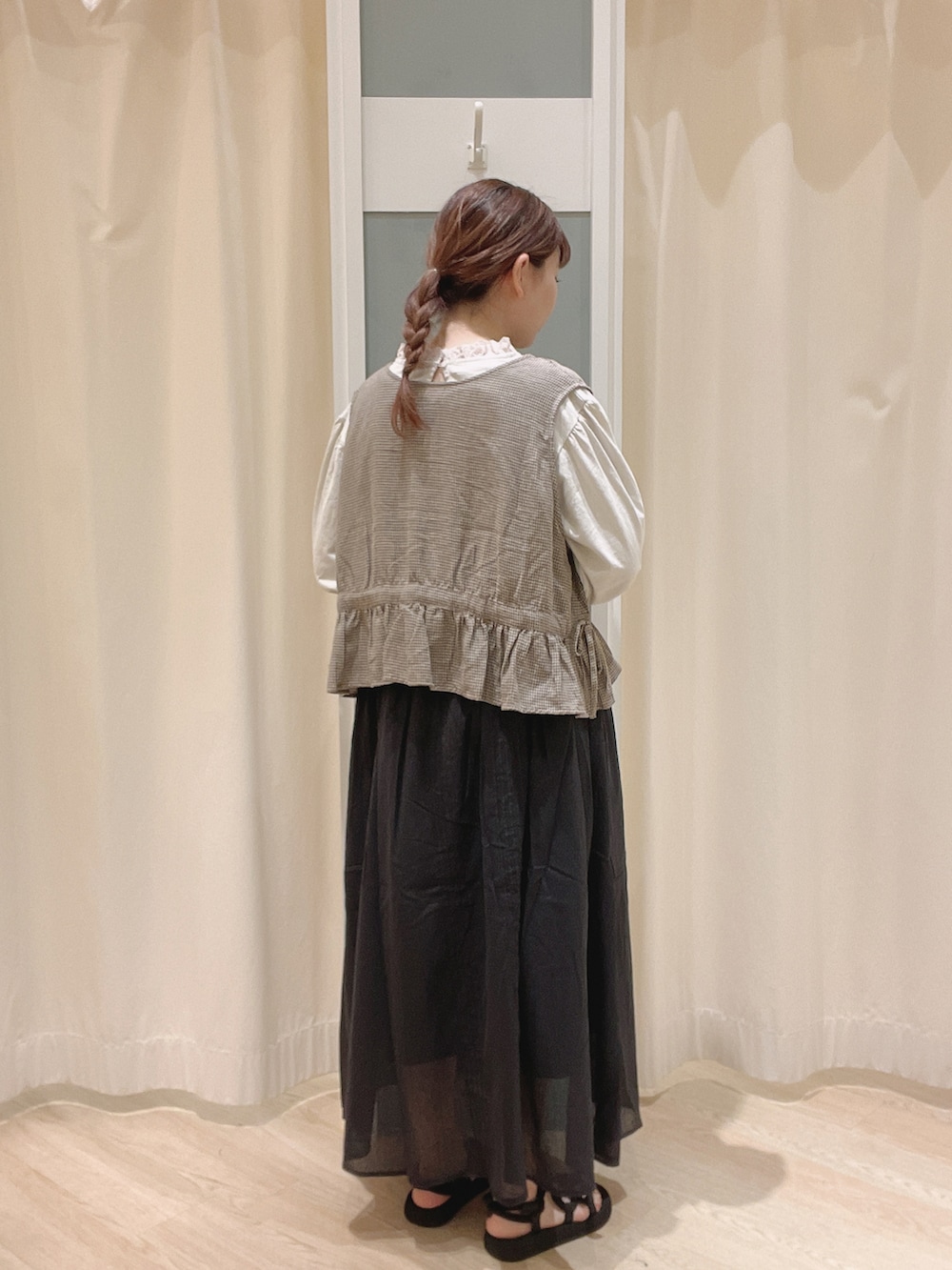 ブラック系のサンダル、ブラック系のスカート、グレー系のベストを着用したレディースの夏コーディネートの2枚目の写真