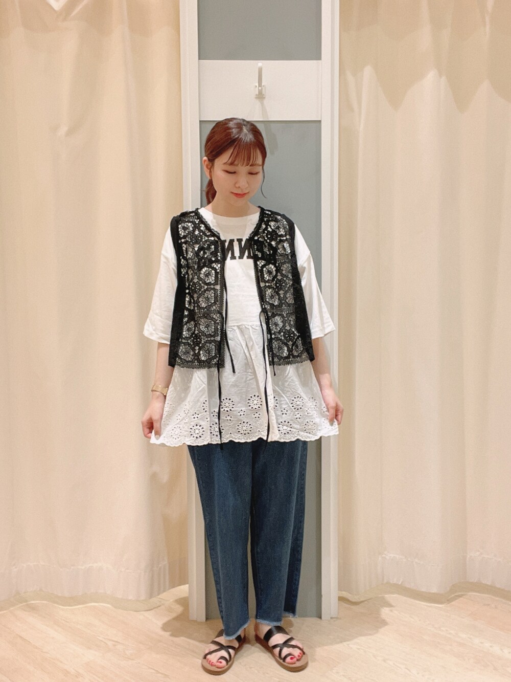 ブラウン系のサンダル、ブルー系のデニムパンツ、ブラック系のベストを着用したレディースの夏コーディネートの2枚目の写真