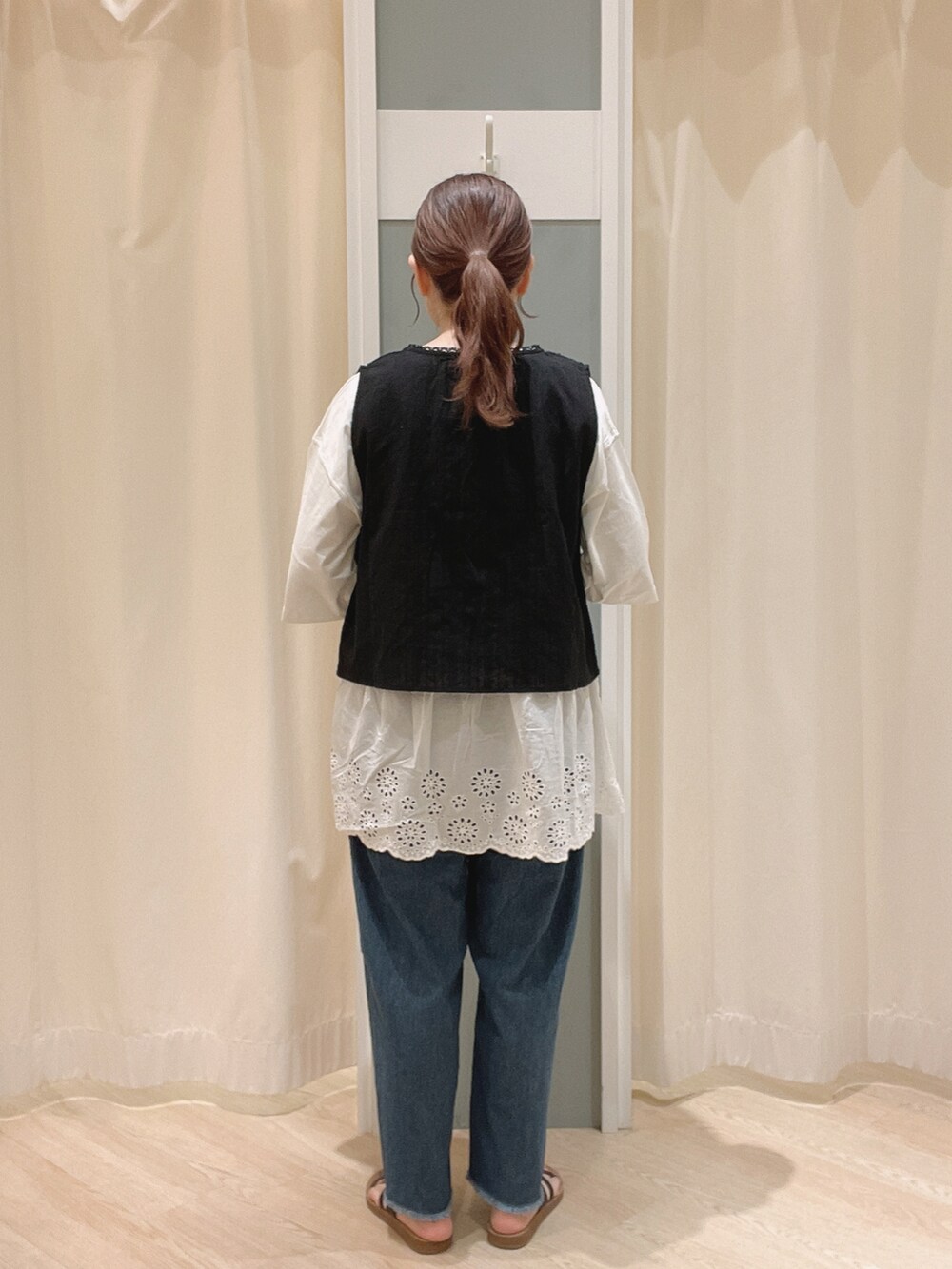 ブラウン系のサンダル、ブルー系のデニムパンツ、ブラック系のベストを着用したレディースの夏コーディネートの4枚目の写真