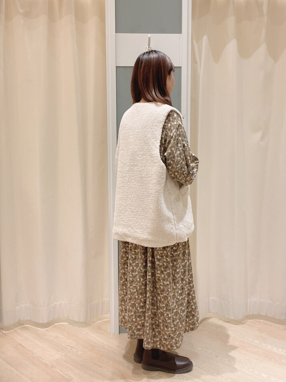 ベージュ系のワンピース、ブラウン系のブーツ、ホワイト系のベストを着用したレディースの秋コーディネートの2枚目の写真