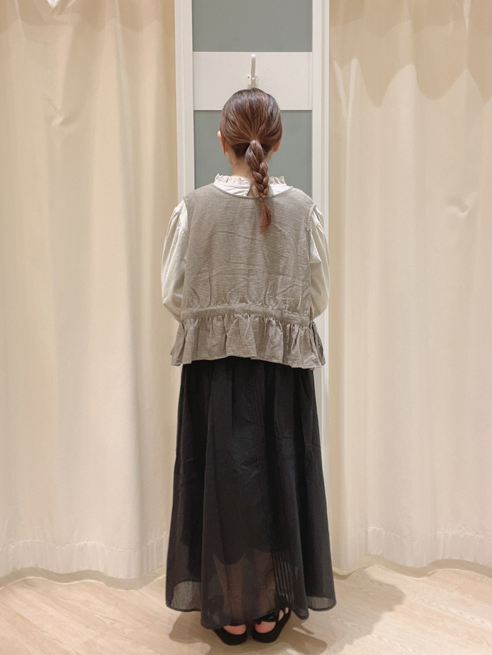 ブラック系のサンダル、ブラック系のスカート、グレー系のベストを着用したレディースの夏コーディネートの3枚目の写真