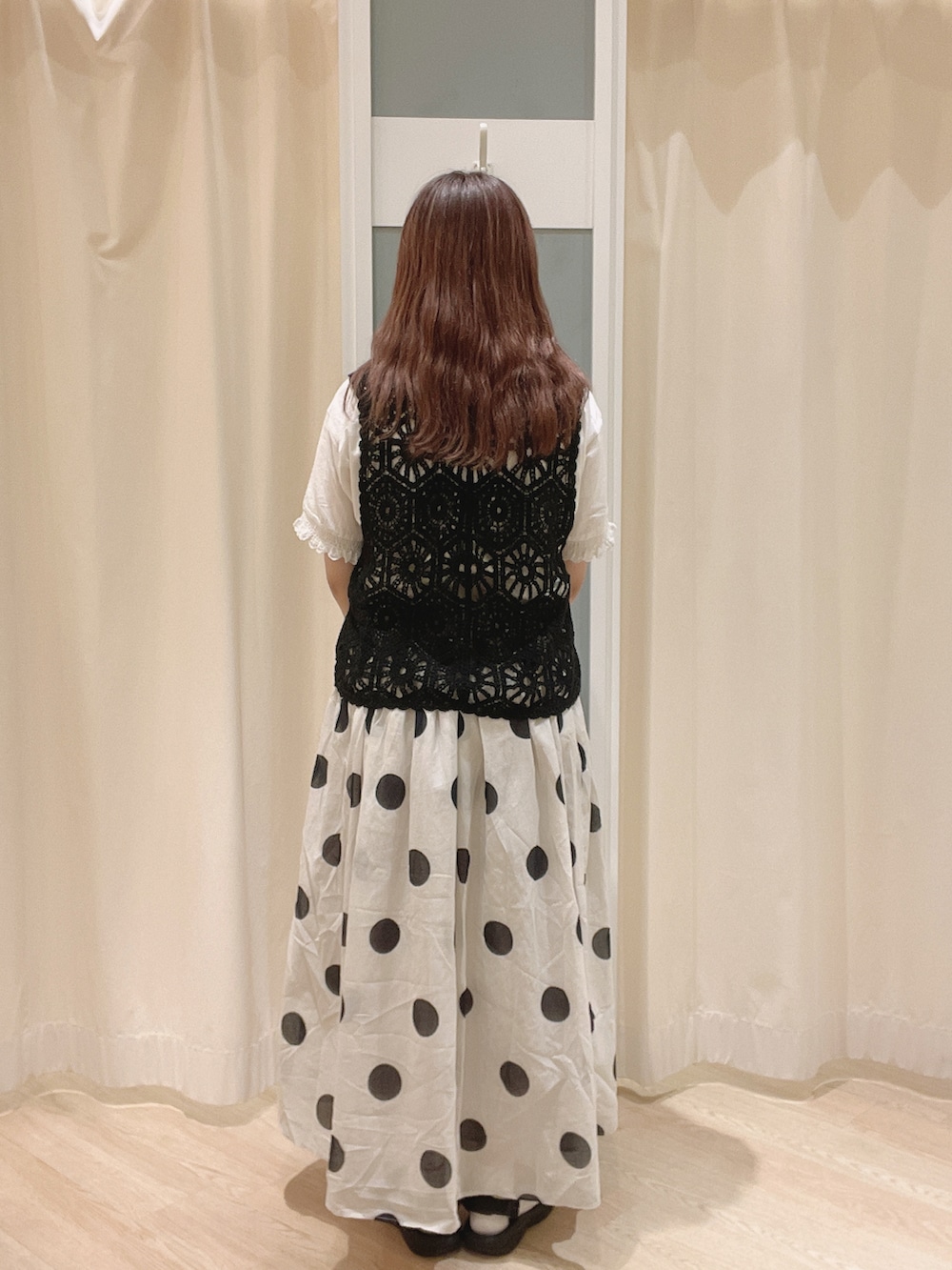 ホワイト系のスカート、ブラック系のサンダル、ブラック系のベストを着用したレディースの夏コーディネートの3枚目の写真