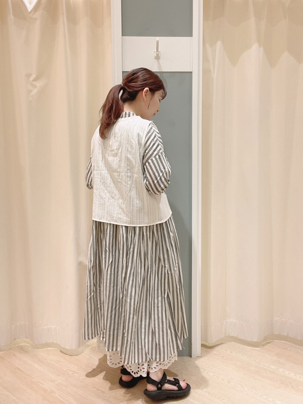 ブラック系のサンダル、ホワイト系のスカート、ホワイト系のベストを着用したレディースの夏コーディネートの2枚目の写真