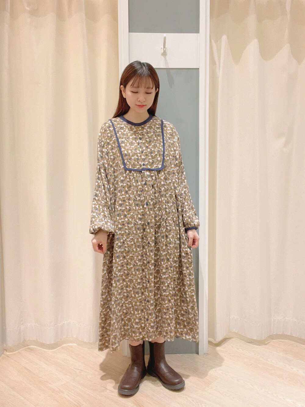 ベージュ系のワンピース、ブラウン系のブーツ、ホワイト系のベストを着用したレディースの秋コーディネートの4枚目の写真