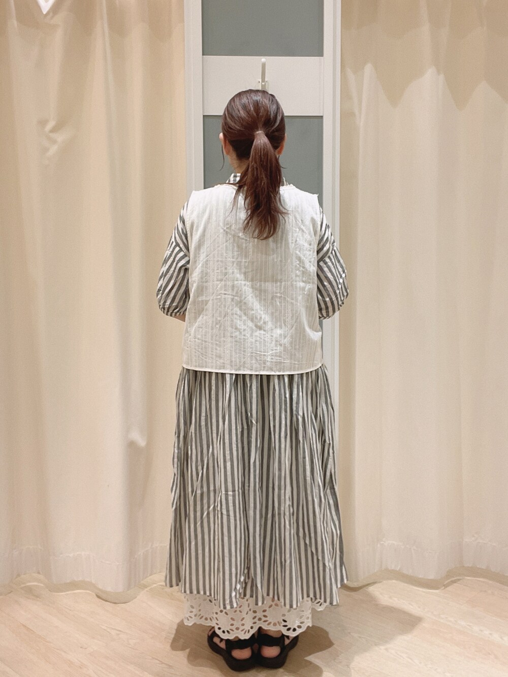 ブラック系のサンダル、ホワイト系のスカート、ホワイト系のベストを着用したレディースの夏コーディネートの3枚目の写真